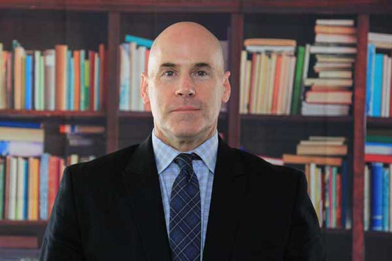 Anthony Shull, Senior Director stands in front of shelves of books
