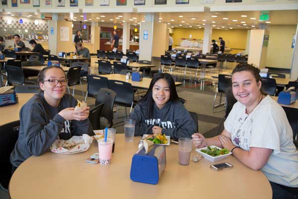 Three College quest students sit around a cafeteria table