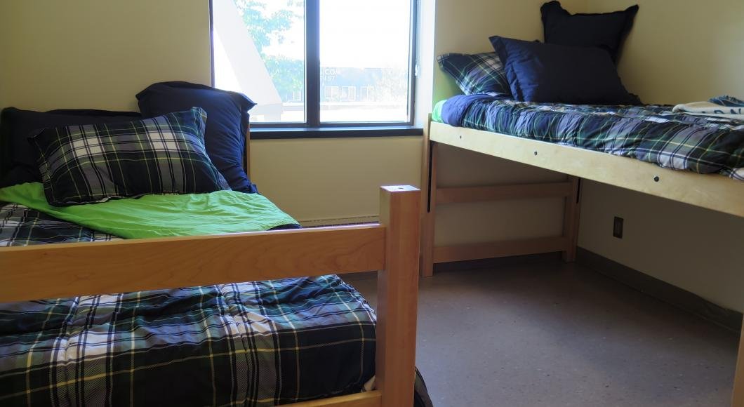 Dorm room with two bunks dressed out in blue and green