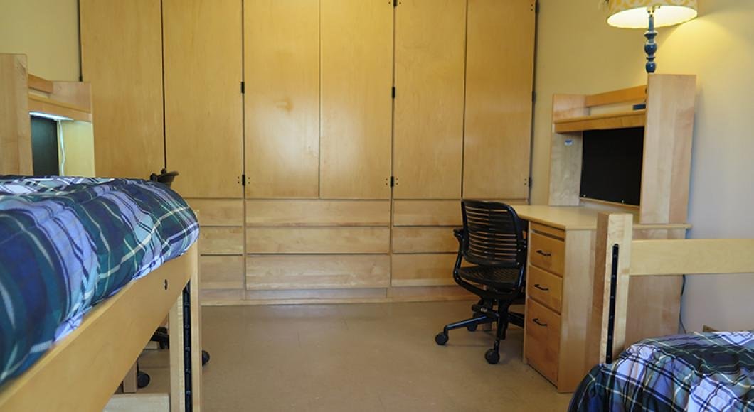 Apartment style dormitory with bunks on either side of the room and closets along the back