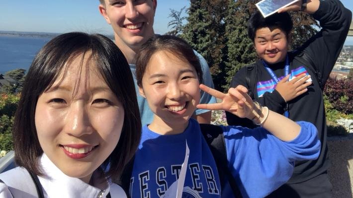 alt="4 students take a selfie on a beautiful, blue sky day"