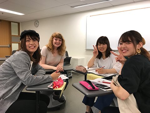 4 women sit around in a group setting inside a classroom