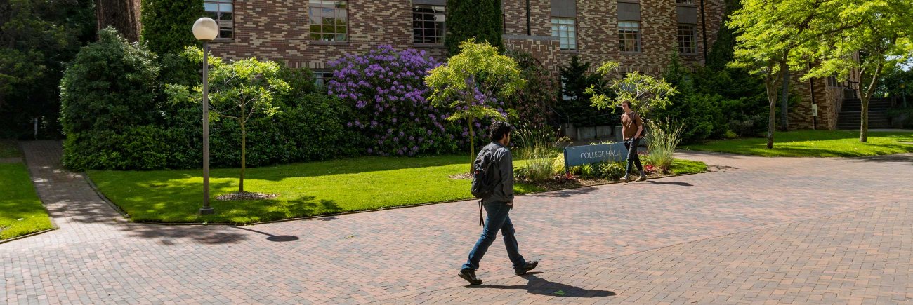 Two students walk in front of College Hall, the home of Outreach and Continuing Education at Western
