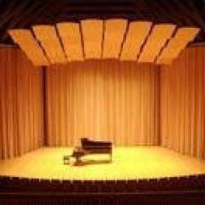stage with yellow lighting and tan curtain, piano in middle