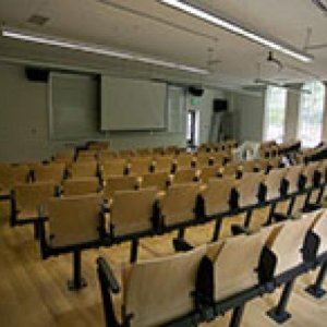 An empty classroom full of empty chairs facing the blank white board at the front of the class.
