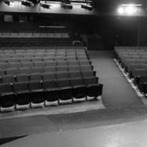 monochrome filtered photo shows rows of seats facing a stage