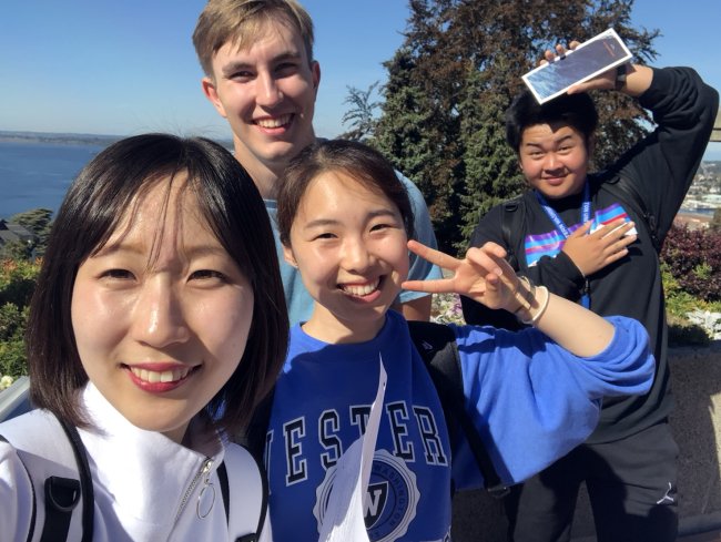 a group of international students are all smiles as they mug for the camera on a blue sky day.