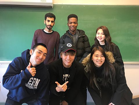 Group of 6 AUAP students standing in front of a chalkboard and smiling a the camera