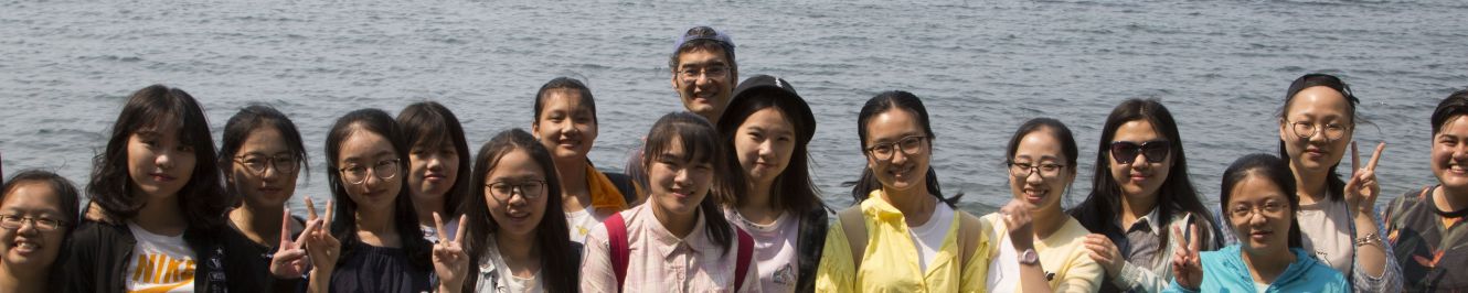 A group of international students stand in front of Bellingham bay enjoying the lovely weather and a day at the beach