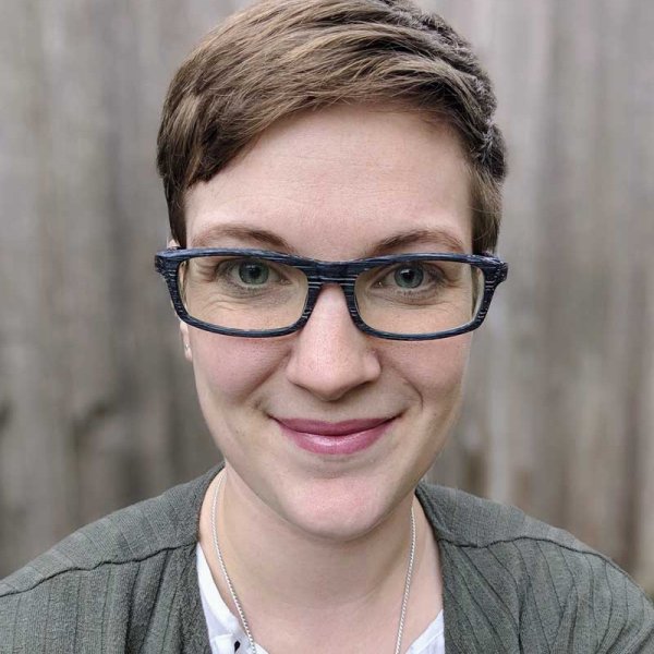 A close up of a smiling sensible woman with short hair, wearing glasses.