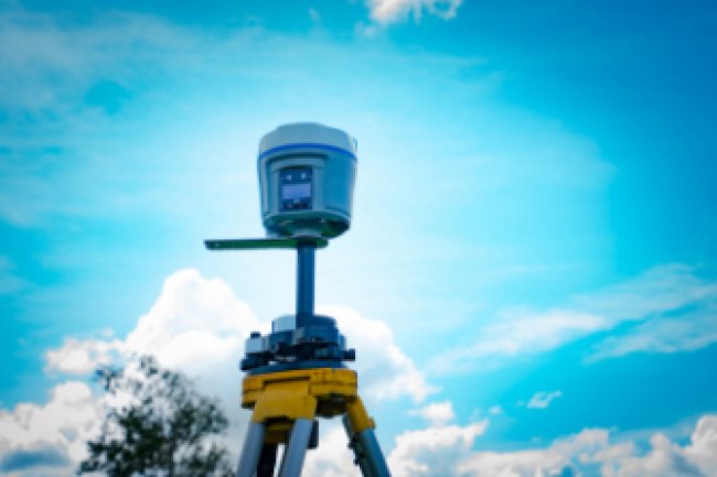 A Surveying tool is silhouetted against the blue sky.